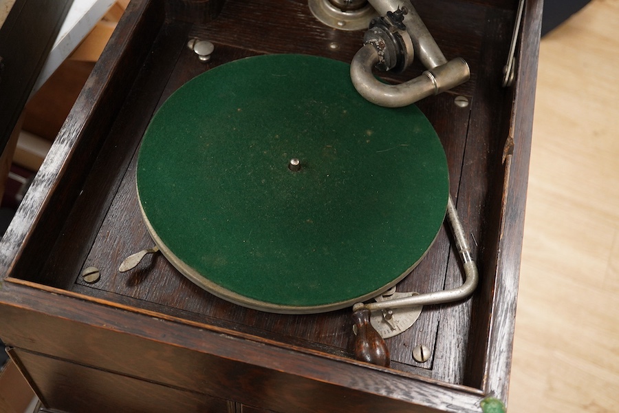 Two gramophone players; an oak cased HMV tabletop gramophone on a similar style mahogany gramophone record stand, height of stand 72.5cm, together with a May-Fair Deluxe Model portable gramophone player. Condition - poor